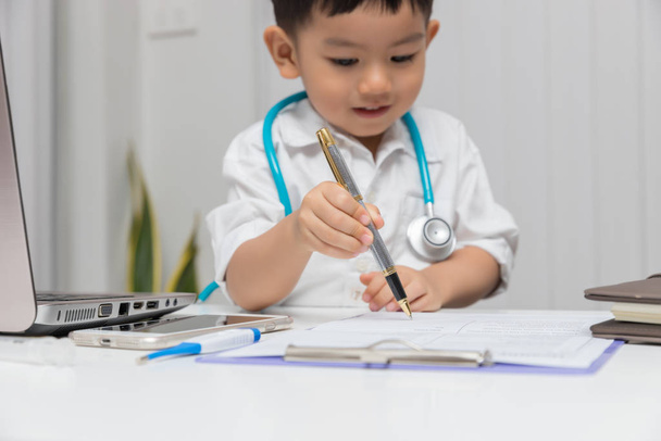 Young asian boy playing doctor and using computer laptop. - Фото, зображення