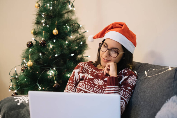 Cute woman with Santa hat looking at laptop - Valokuva, kuva