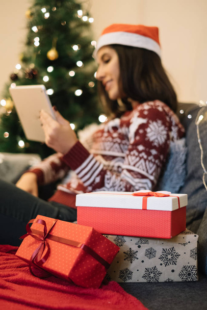 Colored gift boxes for Christmas and blurred woman looking at tablet - Foto, Imagem
