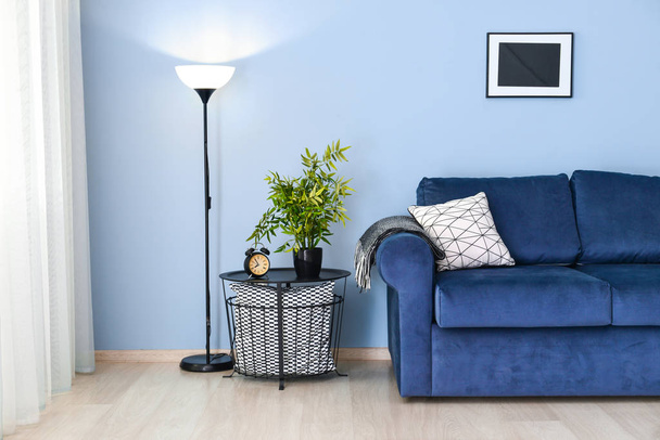 Interior of modern room with blue sofa and table near color wall - Photo, Image