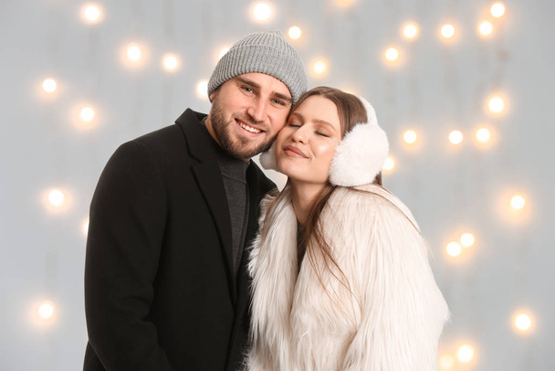 Portrait of happy couple in winter clothes against blurred Christmas lights - Fotó, kép