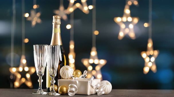 Champagne with gift and decor on table against blurred lights - Photo, Image