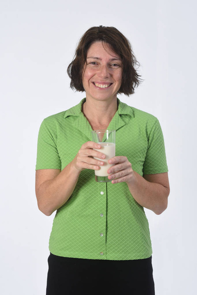 Mujer con vaso de leche sobre fondo blanco
 - Foto, Imagen