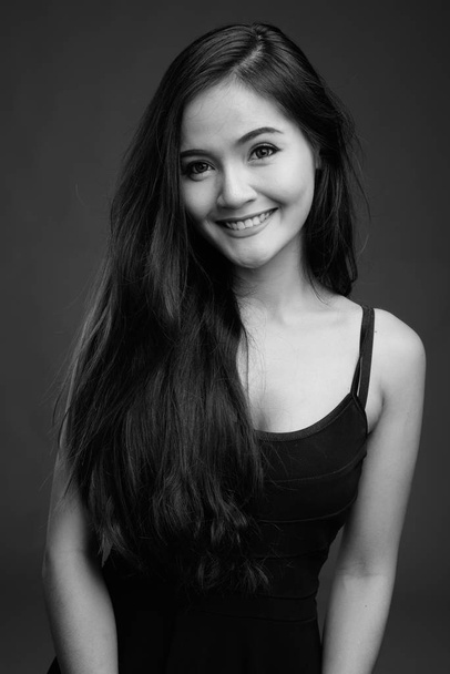 Nuori kaunis aasialainen nainen harmaata taustaa vasten
 - Valokuva, kuva