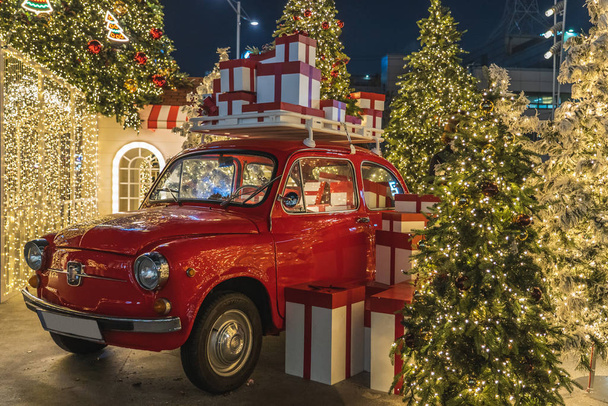 Vermelho velho carro vintage trazendo um monte de presentes com vibrações de Natal iluminação
 - Foto, Imagem
