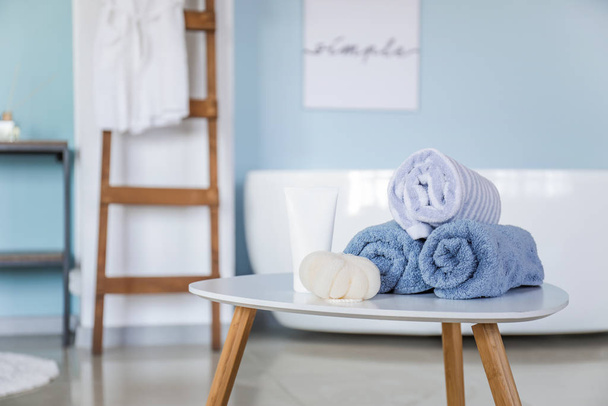 Schone handdoeken met cosmetica en bast wisp op tafel in de badkamer - Foto, afbeelding
