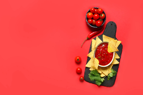 Board with tasty nachos and sauce on color background - Photo, Image