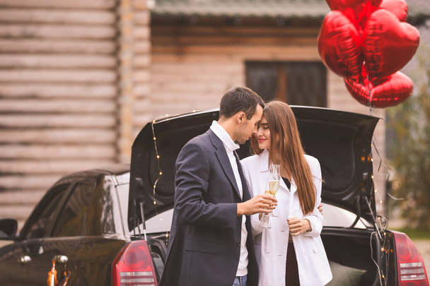 Joyeux jeune couple buvant du champagne près de la voiture à l'extérieur. Fête de la Saint-Valentin
 - Photo, image