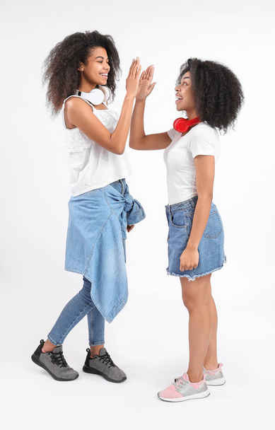 Portrait of young African-American women giving each other high-five on white background - Photo, Image