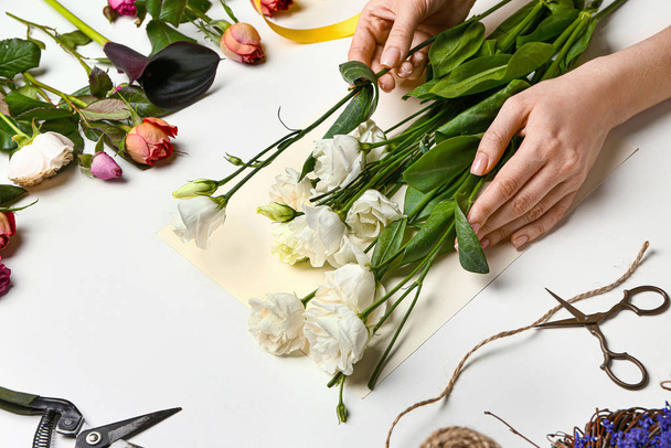 Female florist making beautiful bouquet on white background - Фото, зображення