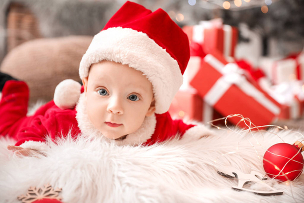 Roztomilé děťátko v kostýmu Santa Clause ležící na kostkovaném doma - Fotografie, Obrázek