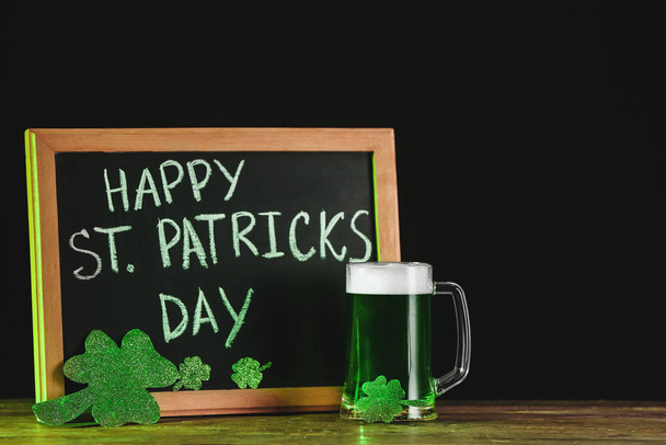 Groen bier en bord met tekst Happy St. Patrick 's Day op tafel - Foto, afbeelding