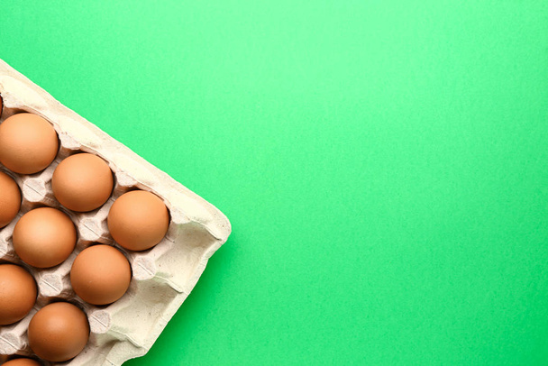 Package with fresh eggs on color background - 写真・画像