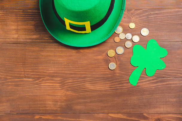 Hat of leprechaun with clover and coins on wooden background. St. Patrick's Day celebration - Photo, Image