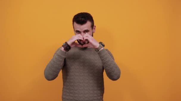Unhappy handsome caucasian man doing shape of heart, looking angry - Imágenes, Vídeo