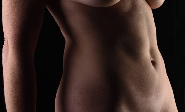 brzuch kobiety w średnim wieku na czarnym tle - Zdjęcie, obraz