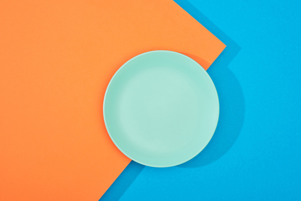 вид сверху на пустую тарелку на красочной синей и оранжевой поверхности
 - Фото, изображение