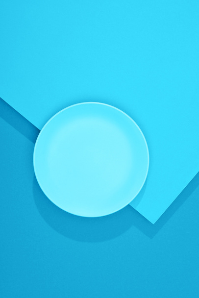 вид сверху на пустую тарелку на красочной голубой поверхности
 - Фото, изображение