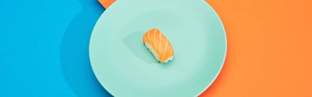 fresh nigiri with salmon on blue and orange surface, panoramic shot - 写真・画像