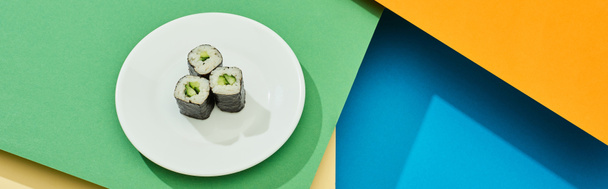 fresh maki with cucumber on plate on multicolored surface, panoramic shot - Photo, Image