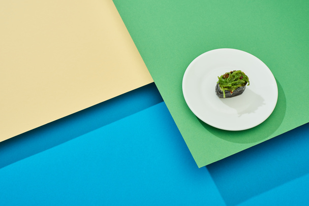 fresh nigiri with seaweed on plate on multicolored surface - Zdjęcie, obraz