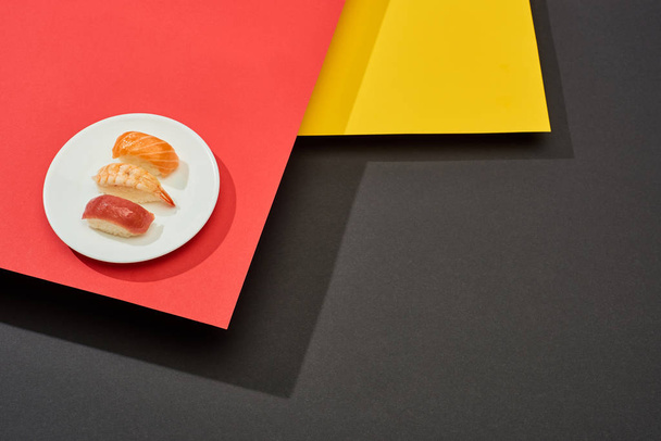 fresh nigiri with salmon, shrimp and tuna on red, yellow and black surface - Photo, Image