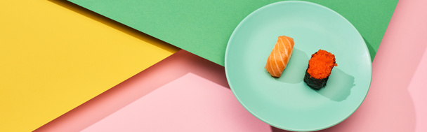 fresh nigiri with salmon and red caviar on yellow, pink, green background, panoramic shot - 写真・画像