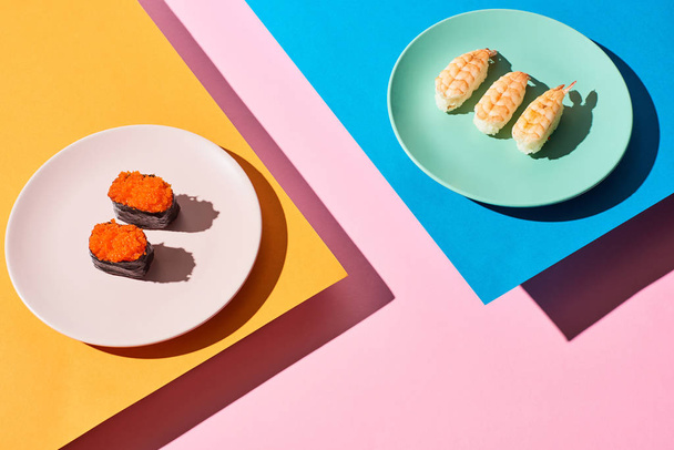 nigiri fresco con camarones y caviar rojo sobre fondo azul, rosa, naranja
 - Foto, Imagen
