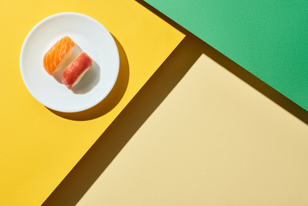 top view of fresh nigiri with salmon and tuna on green and yellow surface - Photo, Image