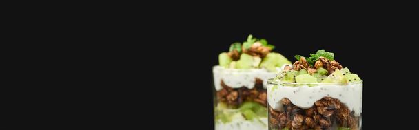 selectieve focus van verse granola met kiwi en yoghurt geïsoleerd op zwart, panoramisch schot - Foto, afbeelding