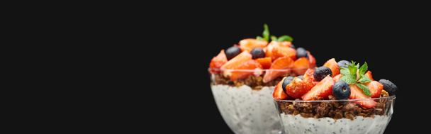 selective focus of fresh granola with berries and chia seeds isolated on black, panoramic shot - 写真・画像