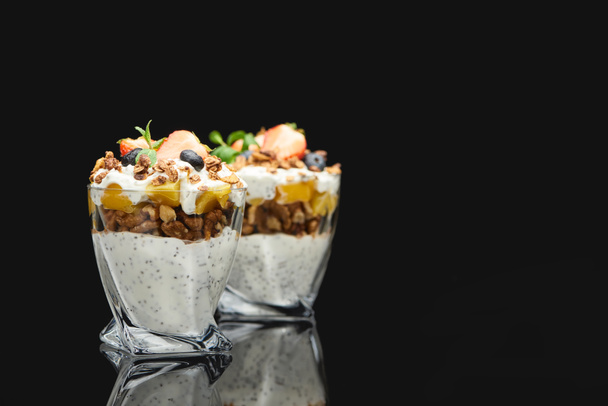 selective focus of fresh granola with canned peach, berries, walnuts and chia seeds isolated on black - Photo, Image