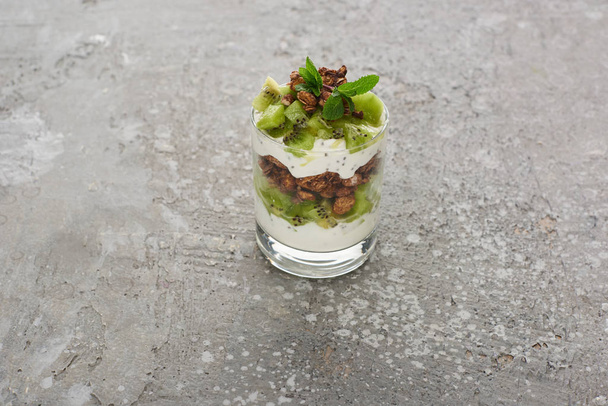 muesli freschi con kiwi e yogurt in vetro su superficie di cemento grigio
 - Foto, immagini