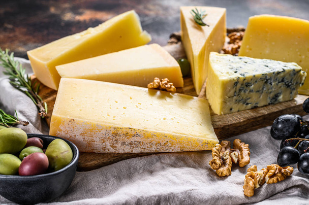 Sammlung von schweizer, holländischer, französischer, italienischer Käse mit Nüssen und Trauben. Dunkler Hintergrund. Ansicht von oben - Foto, Bild
