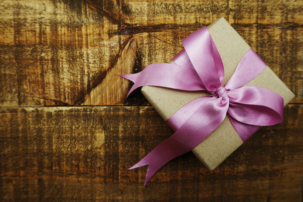 Gift box with pink ribbon on wooden background - Foto, Imagen