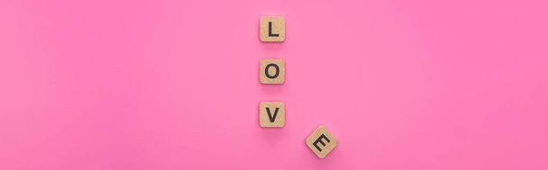 bovenaanzicht van liefdesbelettering op houten blokjes geïsoleerd op roze achtergrond, panoramisch beeld - Foto, afbeelding