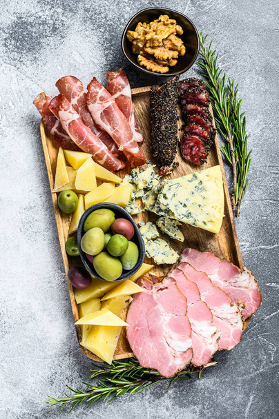 Antipasto schotel met ham, prosciutto, salami, blauwe kaas, mozzarella en olijven. Grijze achtergrond. Bovenaanzicht - Foto, afbeelding