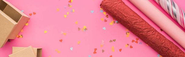 felső kilátás Valentin konfetti, csomagolópapír, ajándék dobozok rózsaszín háttér, panoráma lövés - Fotó, kép