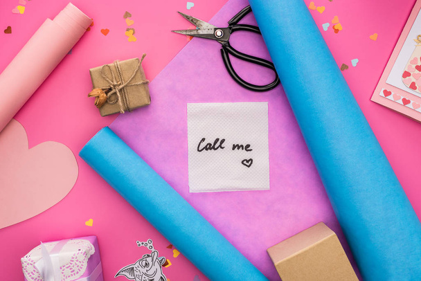 top kilátás Valentin dekoráció, csomagolópapír, ajándékdobozok, olló és kártya hívó felirattal rózsaszín háttér - Fotó, kép