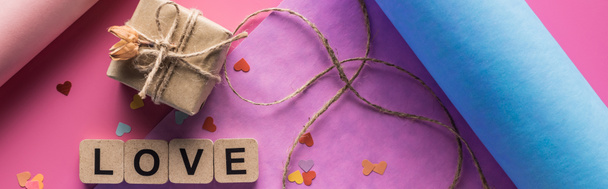 κορυφαία άποψη της διακόσμησης του Αγίου Βαλεντίνου, χαρτί περιτυλίγματος, σπάγκο, κουτί δώρου και γράμματα αγάπης σε ξύλινους κύβους σε ροζ φόντο, πανοραμική λήψη - Φωτογραφία, εικόνα