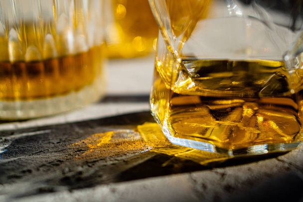 Bardakta viski, parlak güneş ışığı, sarı içki. - Fotoğraf, Görsel