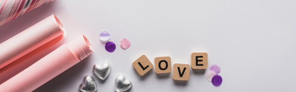 top view of silver hearts, wrapping paper and cubes with love lettering on white background, panoramic shot - Fotografie, Obrázek