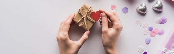 cropped view of woman holding valentines gift box with heart near decoration on white background, panoramic shot - Foto, imagen