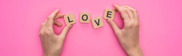 partial view of woman holding cubes with love lettering on pink background, panoramic shot - Fotografie, Obrázek