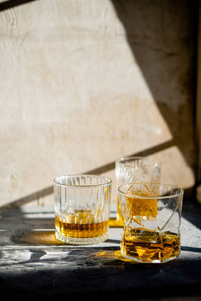Whiskey w szklankach na stole w jasnym słońcu, żółty napój - Zdjęcie, obraz