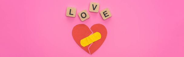 top view of love lettering on wooden cubes near broken heart with patch on pink background - Photo, Image