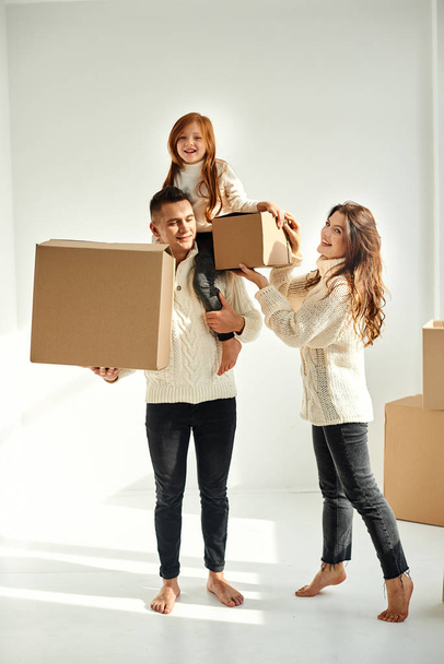 Family unpacking cardboard boxes at new home on a white backgrou - Foto, Imagem