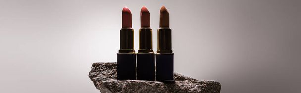 lipsticks on stone in dark on white background with back light, panoramic shot - Zdjęcie, obraz