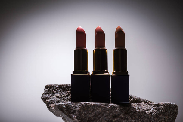 lipsticks on stone in dark on white background with back light - Foto, afbeelding