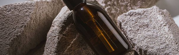 dispensador garrafa cosmética em rochas, tiro panorâmico
 - Foto, Imagem
